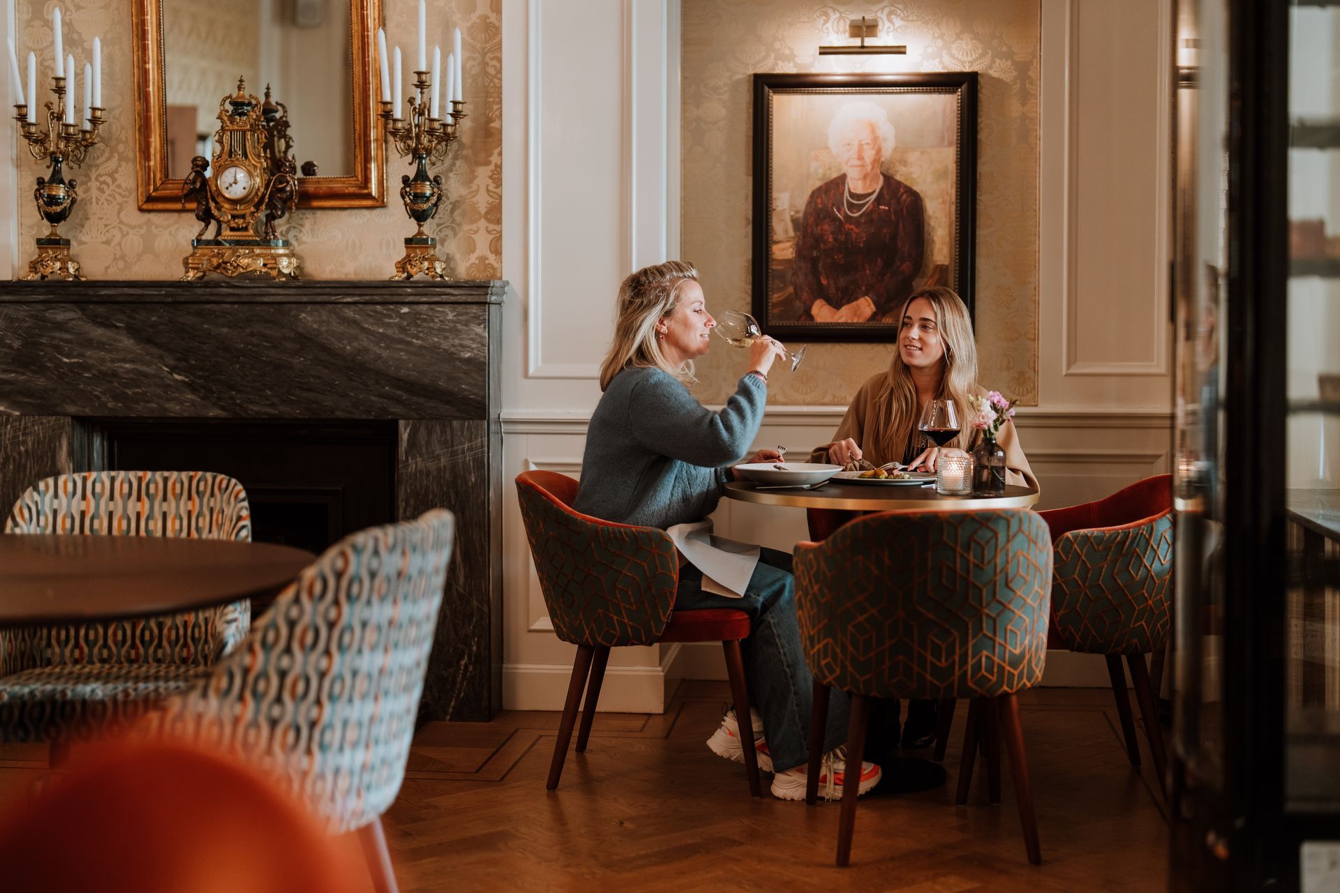 Elegante eettafel gedekt voor een maaltijd, in een kamer met donkerhouten lambrisering en bloemendecoraties.