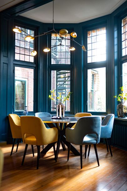 Een vrouw met lang krullend haar steekt haar hand op naar het gevlekte zonlicht in een bosrijke omgeving.