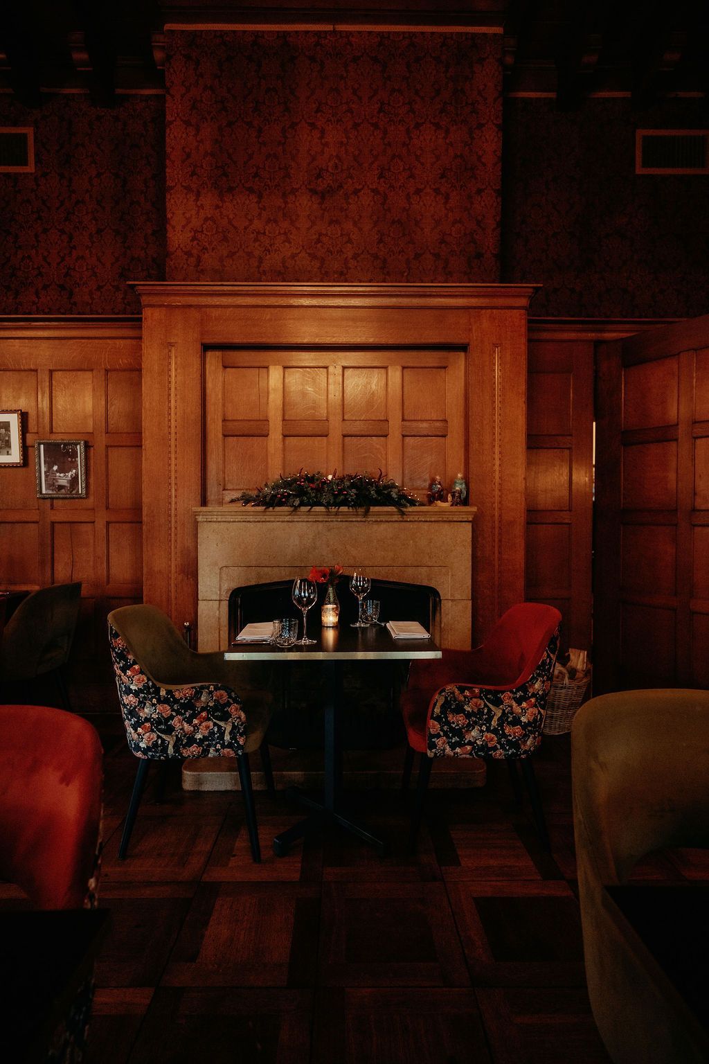 Elegante eetkamer met groene kast, kroonluchter en een houten tafel gedekt met drankjes en bloemen.