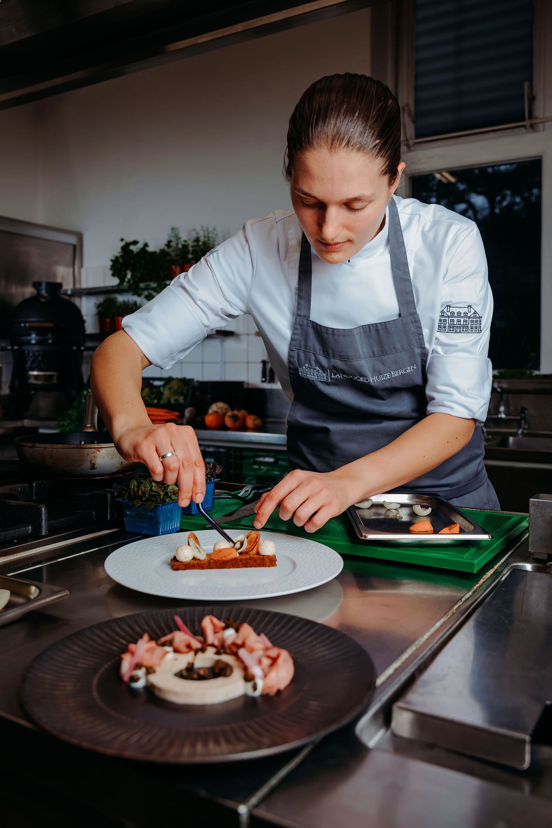 Een groep restaurantmedewerkers poseert voor een gebouw met een glazen deur. Ze dragen schorten, pakken en overhemden en lachen naar de camera.