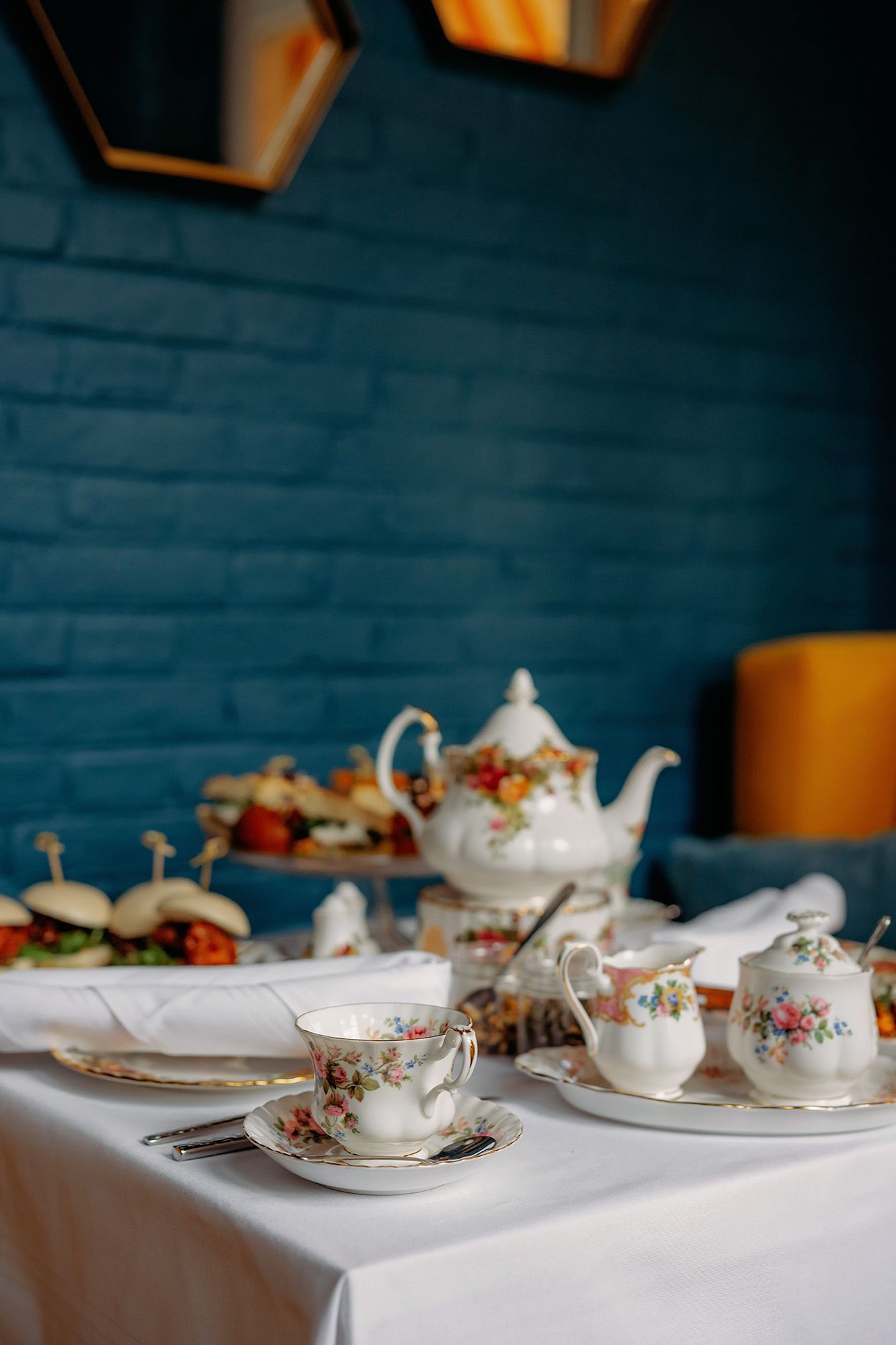 Elegante eetkamer met gedekte tafels voor maaltijden, sierlijk gouden behang, donkere houten lambrisering en kroonluchters.