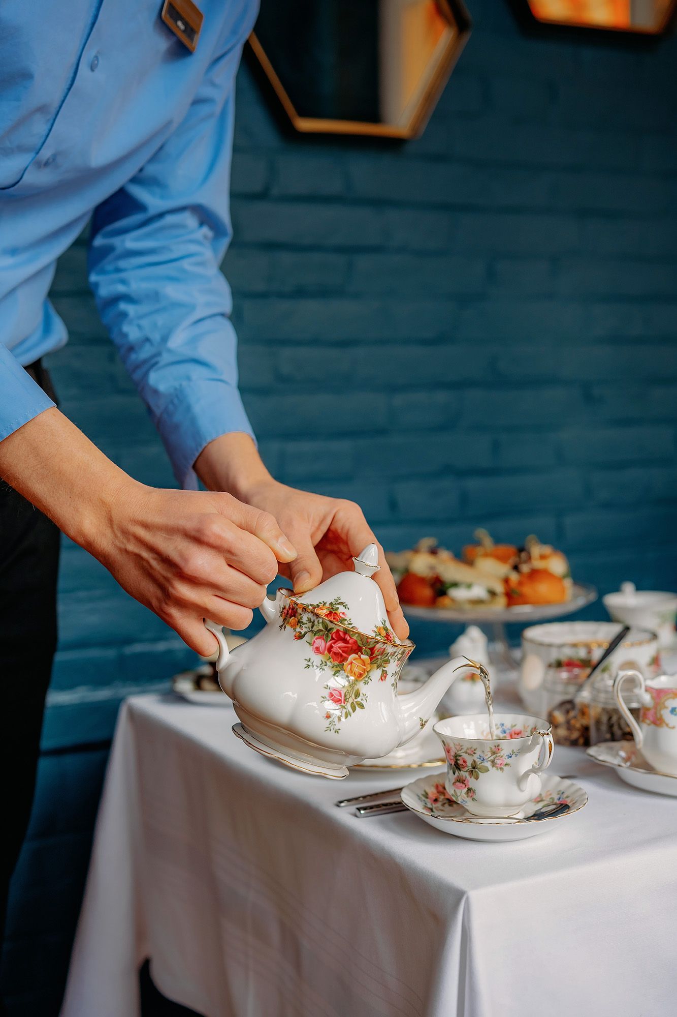 Een pasgetrouwd stel loopt hand in hand door een tuin en zwaait naar de camera. Het bruidspaar staat voor een groot met klimop begroeid gebouw. De bruidegom draagt een rood pak en de bruid een witte jurk.