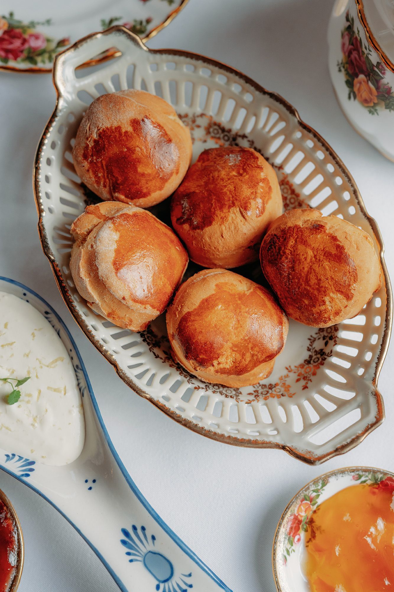Een rijkelijk gedecoreerde eetkamer met een erker, een kroonluchter en gedekte tafels voor een maaltijd. Rode en gouden accenten domineren de ruimte.