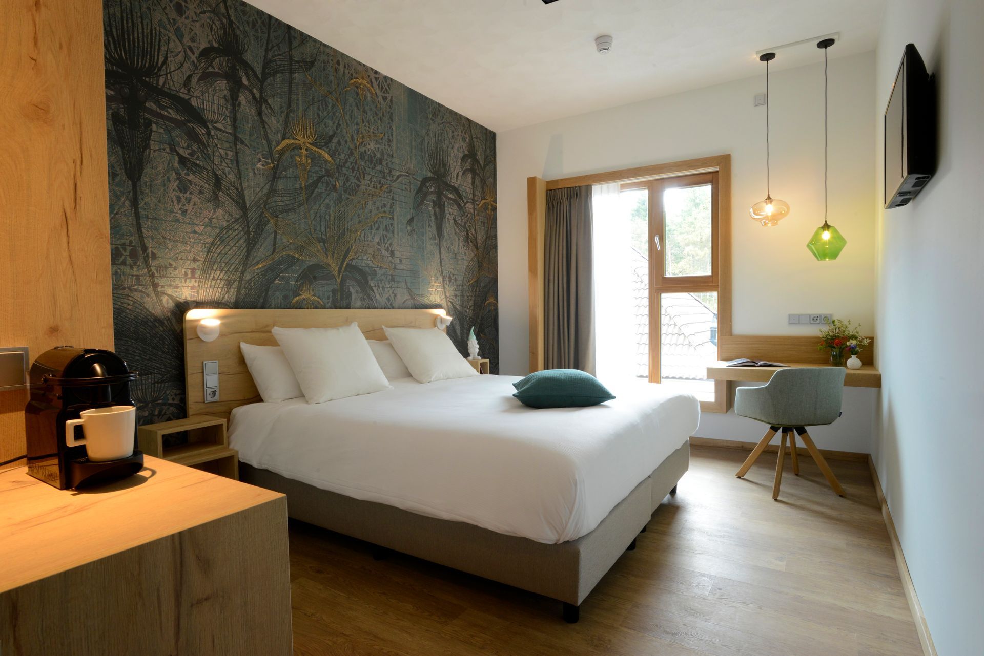 Hotel room with a bed, desk, and coffee machine; dark mural on the wall.