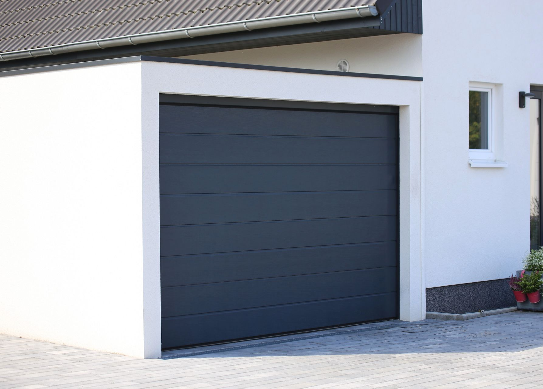 Porte de garage grise sur un bâtiment blanc, faisant partie d'une maison.