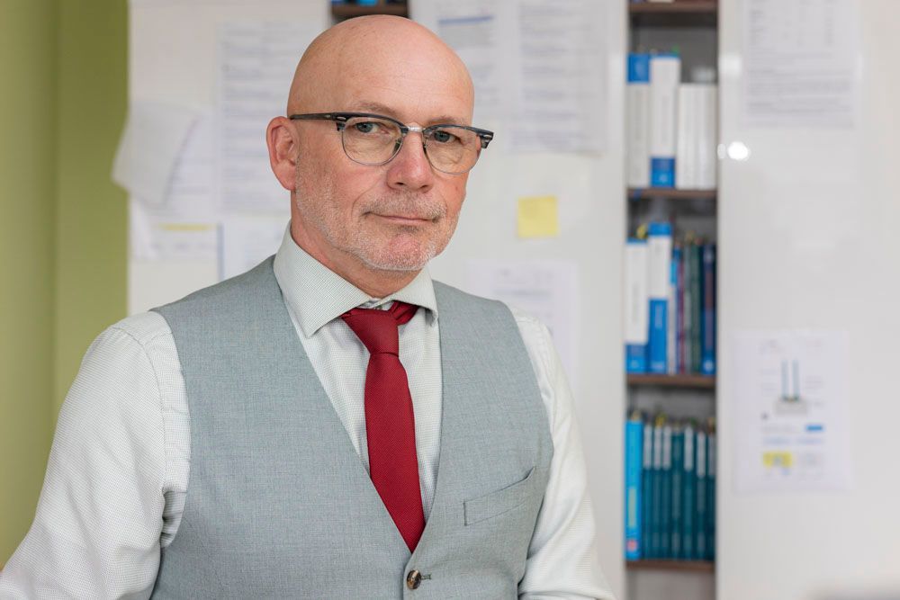 Herr Krüger mit grauer Weste und roter Krawatte