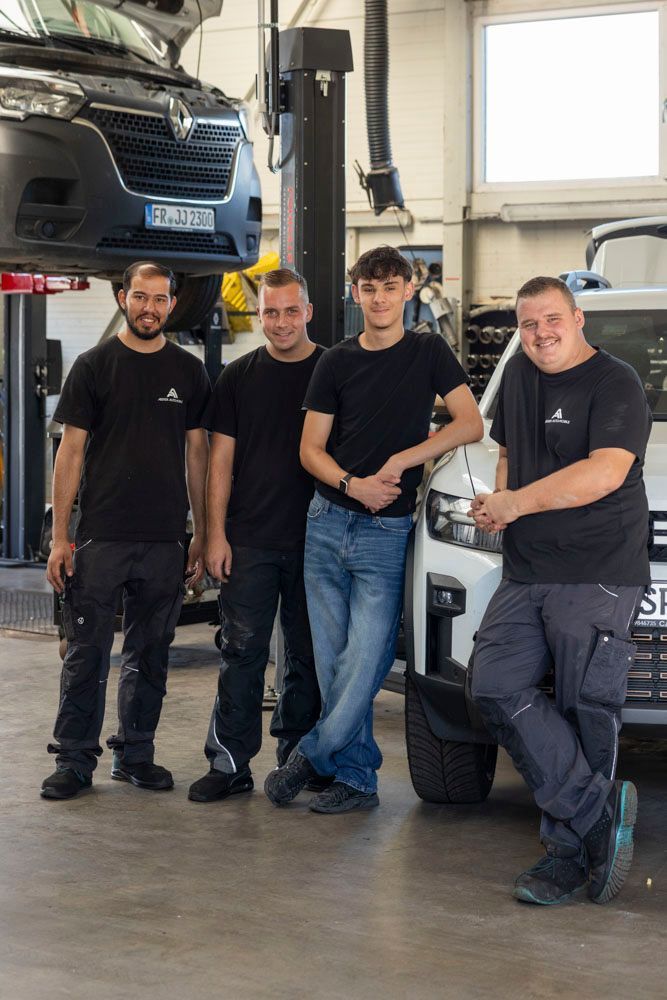 Drei Mechaniker posieren in einer Garage neben einem hochgelegten Lkw und einem Lieferwagen.
