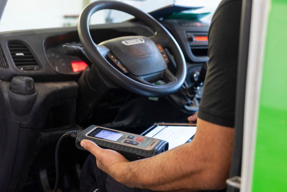 Eine Person hält ein mobiles Gerät im Fahrzeuginnenraum in der Nähe des Lenkrads und des Armaturenbretts.