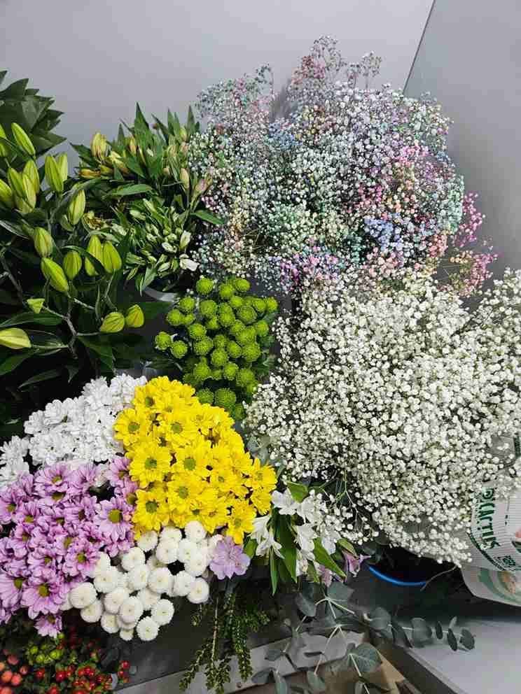 Surtido de flores cortadas de colores, incluidos lirios, giardineras, crisantemos y otras variedades, dispuestas en una floristería.