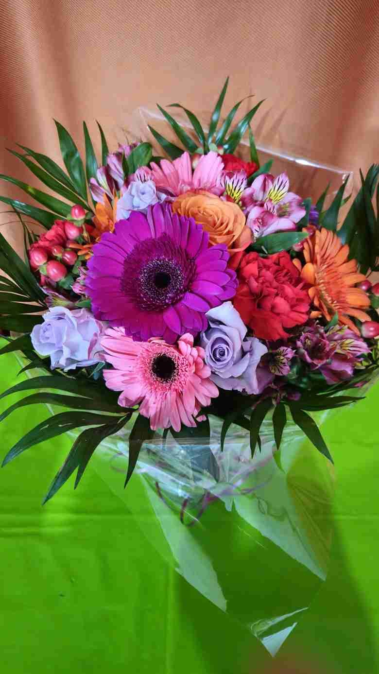 Ramo de flores de colores, entre gerberas, rosas y alstroemerias, envuelto en celofán.