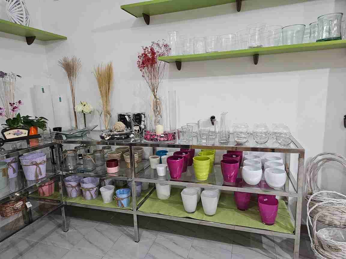 Interior de una floristería con estantes que albergan jarrones, macetas y artículos decorativos.
