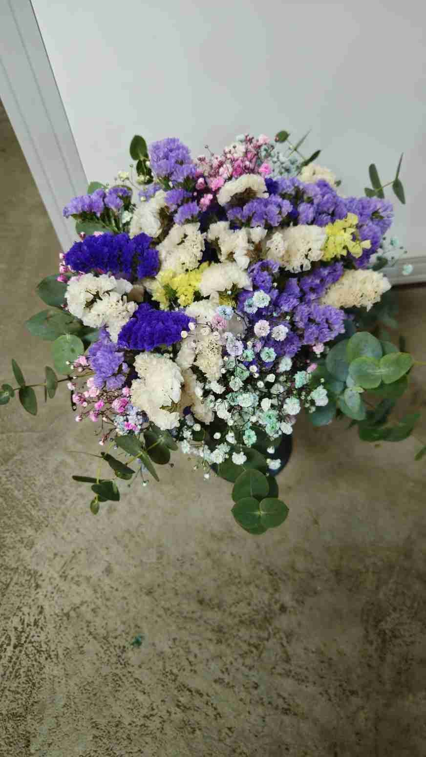 Ramo de flores de colores, entre ellas violeta, blanco y amarillo, con vegetación.