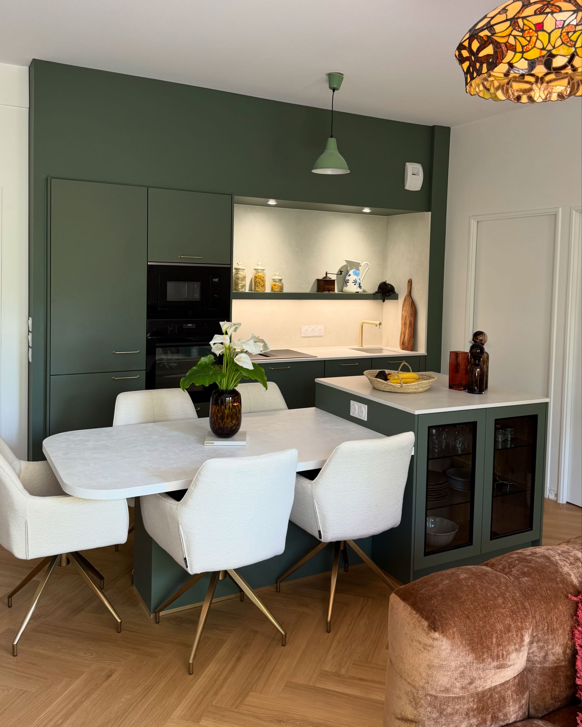 Cuisine en bois avec appareils électroménagers en acier inoxydable, comptoirs beiges et parquet en bois clair.