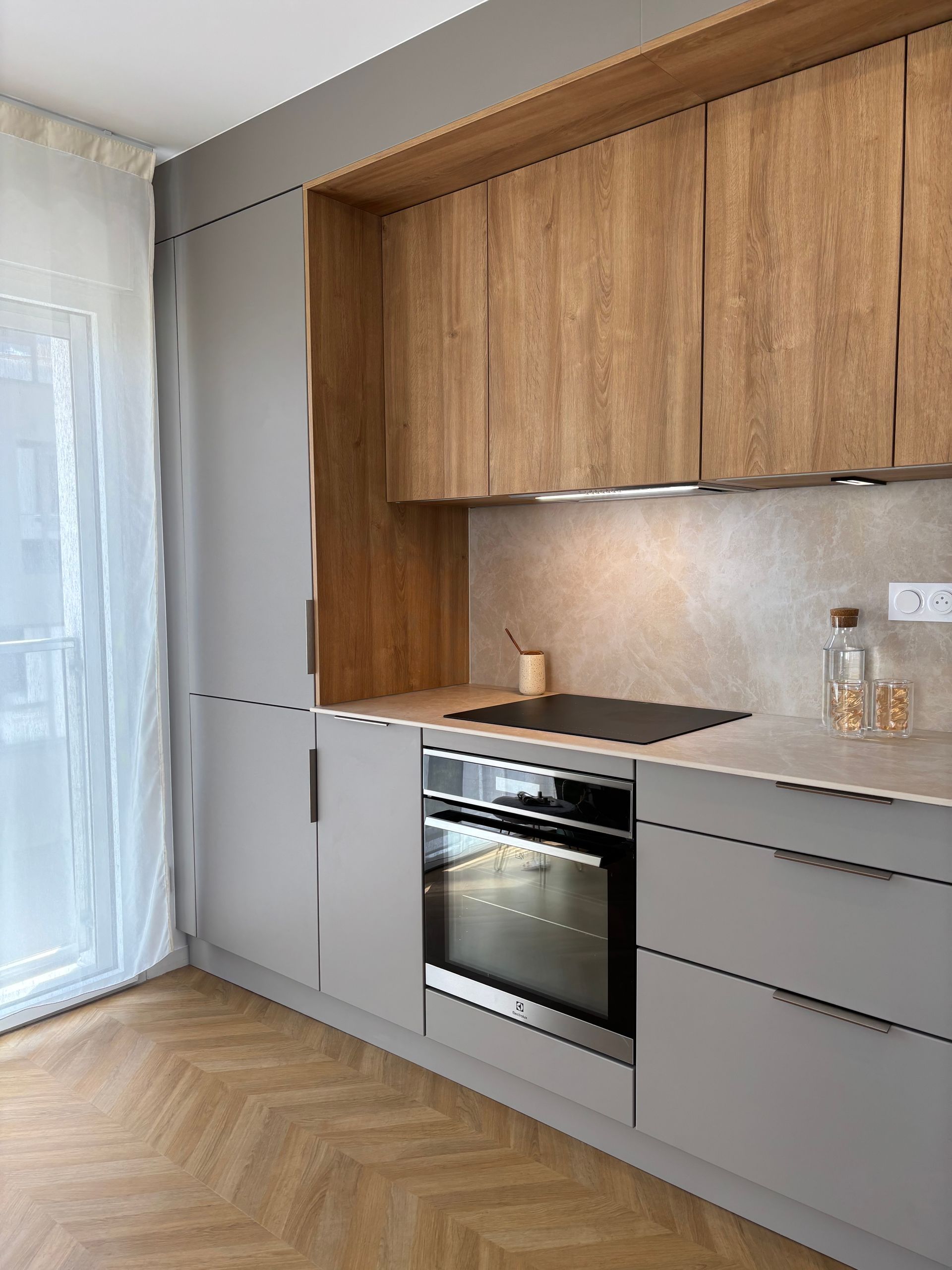 Cuisine blanche avec îlot, luminaires suspendus et tabourets de bar.