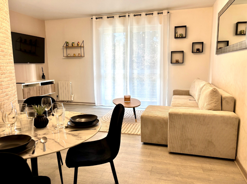 Salle à manger avec des murs couleur moutarde, deux miroirs et une table dressée pour six personnes.