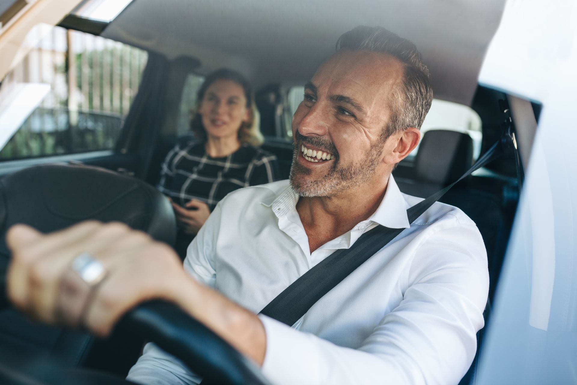 Chauffeur de taxi souriant qui discute avec une cliente assise à l'arrière du véhicule