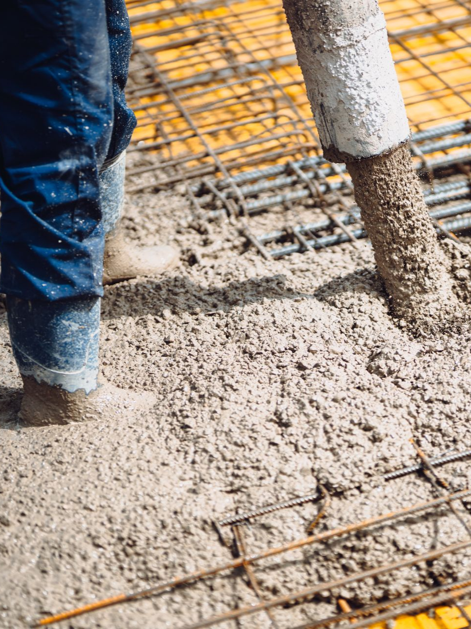 Ouvrier coulant du béton frais sur des barres d'armature sur un chantier de construction