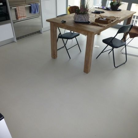 Hellgrauer Boden in einer Küche mit Holztisch, Stühlen und einem Schrank.