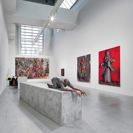 Galerieinterieur, Skulptur einer Person auf einem Betonblock, Gemälde an der Wand.