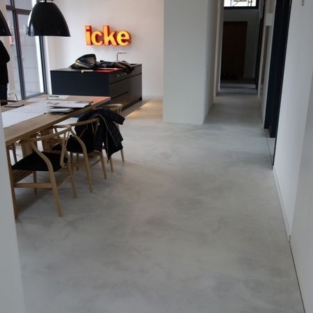 Ein modernes Interieur mit hellgrauem Boden, Essbereich mit Holztisch und Stühlen.