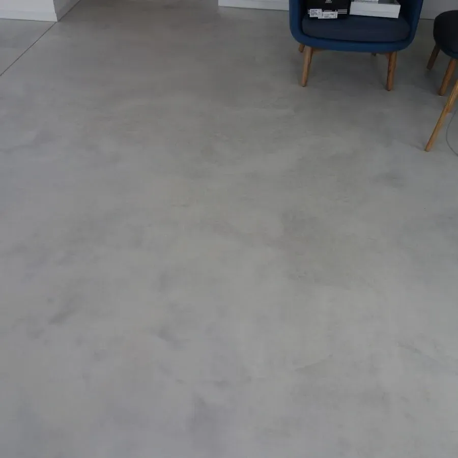 Grauer Betonboden, blauer Stuhl, Holzbeine, modernes Interieur.