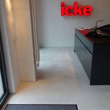 Ein modernes Bürointerieur mit schwarzem Tresen, grauem Boden und rotem „icke“-Schild.