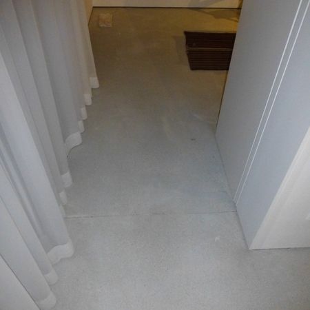 Betonboden in einem Innenflur mit einer Tür und einem Vorhang auf der linken Seite.