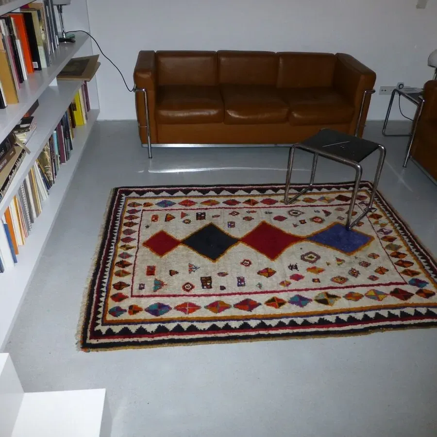 Braunes Ledersofa und gemusterter Teppich in einem modernen Zimmer mit eingebauten Bücherregalen.