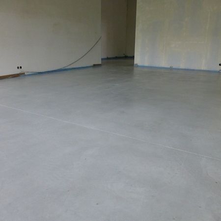 Grauer Betonboden in einem leeren Raum, im Hintergrund die Wände.