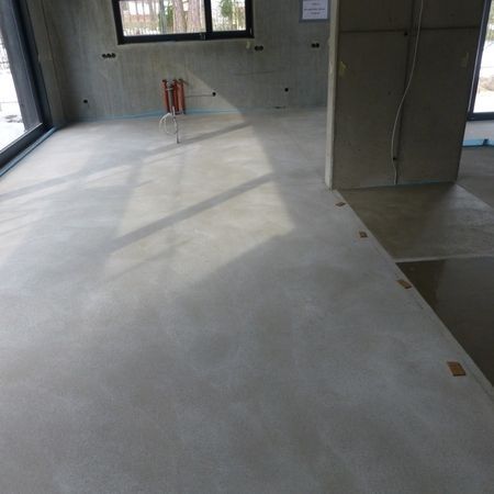 Betonboden in einem unfertigen Innenraum, auf dem Sonnenlicht Schatten wirft.