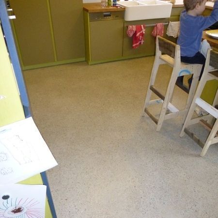 Ein Kind sitzt an einer Küchentheke. Der Raum hat gelbe Schränke und ein weißes Spülbecken.