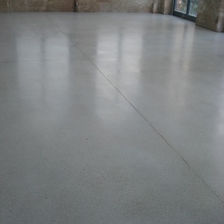 Ein polierter Betonboden in einem Raum, der das Licht der Fenster reflektiert, mit einem durchgehenden Riss.