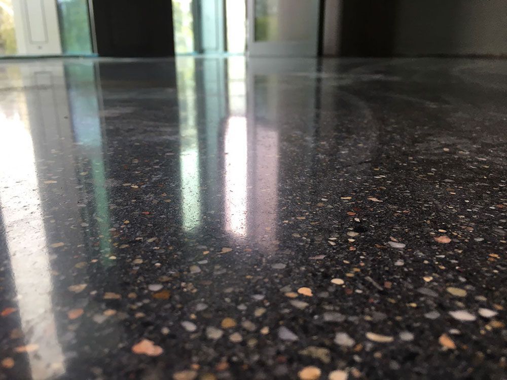 Nahaufnahme eines hochglanzpolierten Betonbodens mit reflektierender Oberfläche, auf dem die Zuschlagstoffe sichtbar sind.