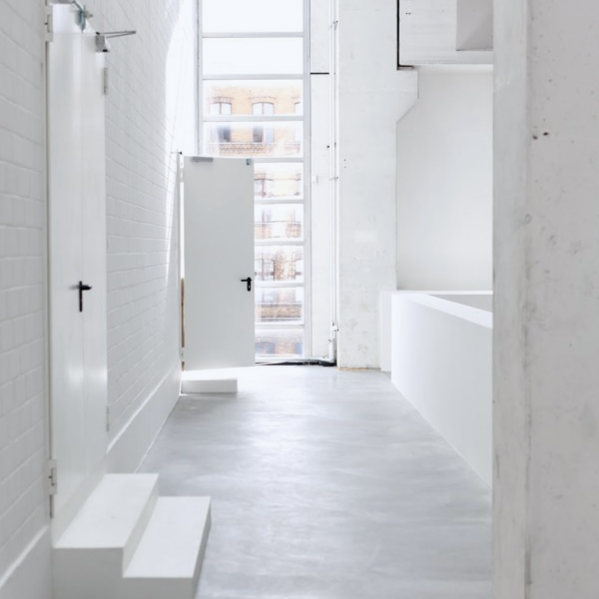 Weißer, minimalistischer Flur mit Türen, Fenster und Stufe.