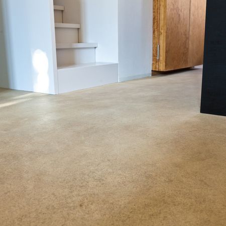 Beiger Boden mit Treppe und Holzschrank.