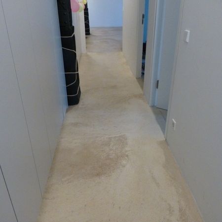 Schmaler Flur mit hellem Boden und weißen Wänden. Türen befinden sich an den Seiten.