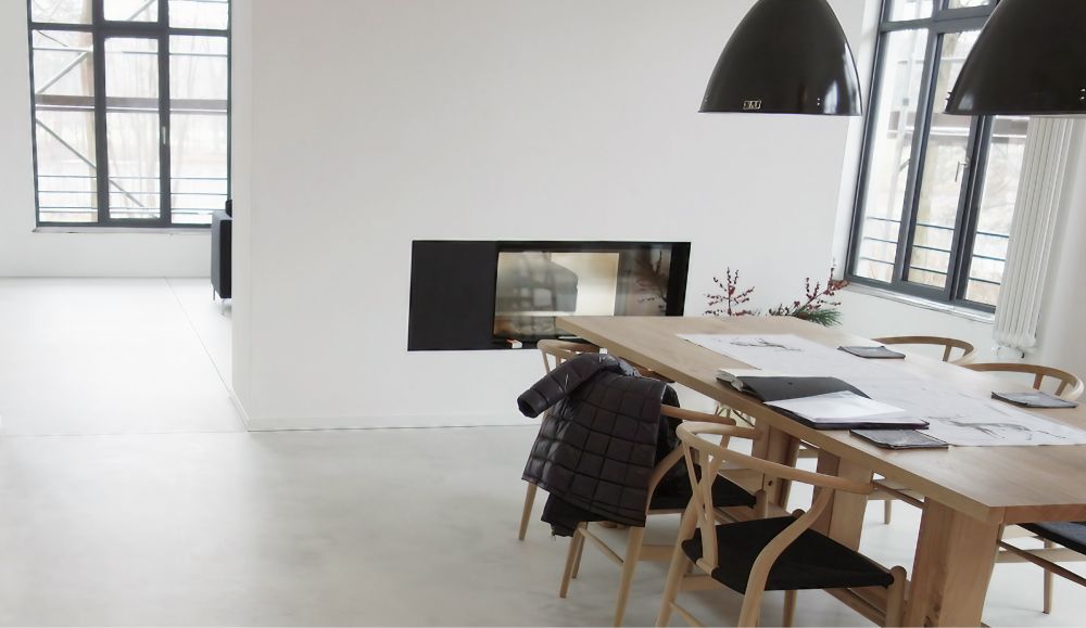 Esszimmer mit langem Holztisch, Kamin und großen Fenstern.