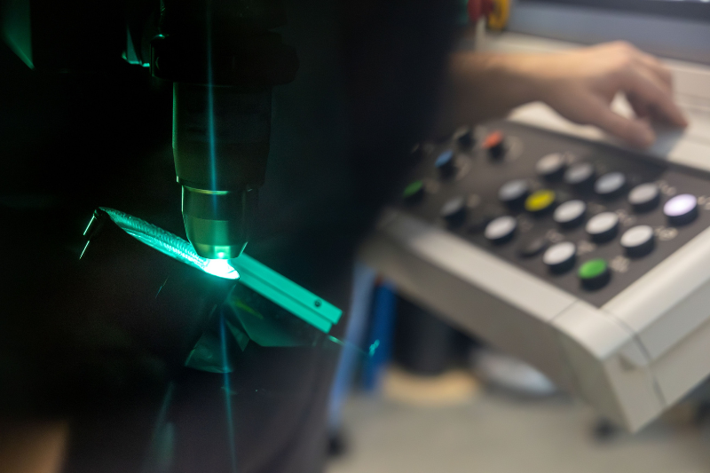 Eine Person verwendet eine Laserschneidmaschine, um ein Stück Metall zu schneiden.