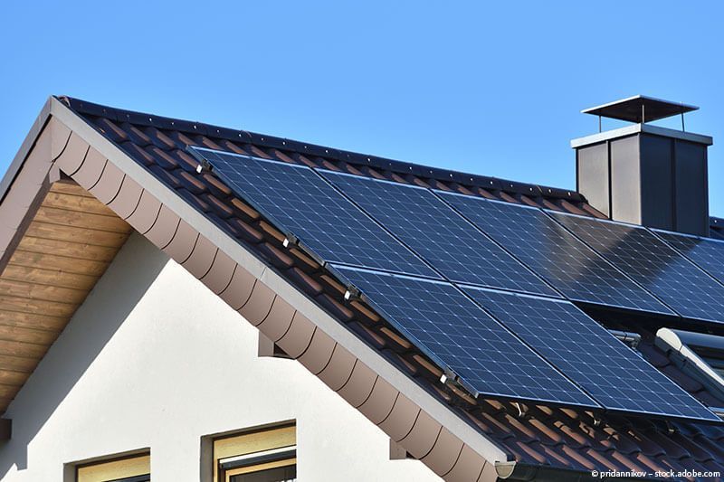 Ein Haus mit Solarzellen auf dem Dach und einem Schornstein.