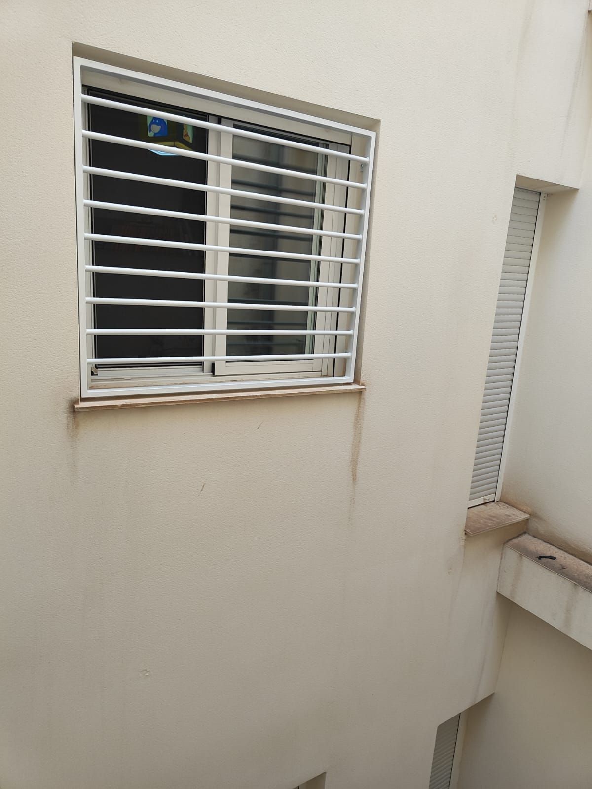 Un edificio blanco con una ventana con rejas.