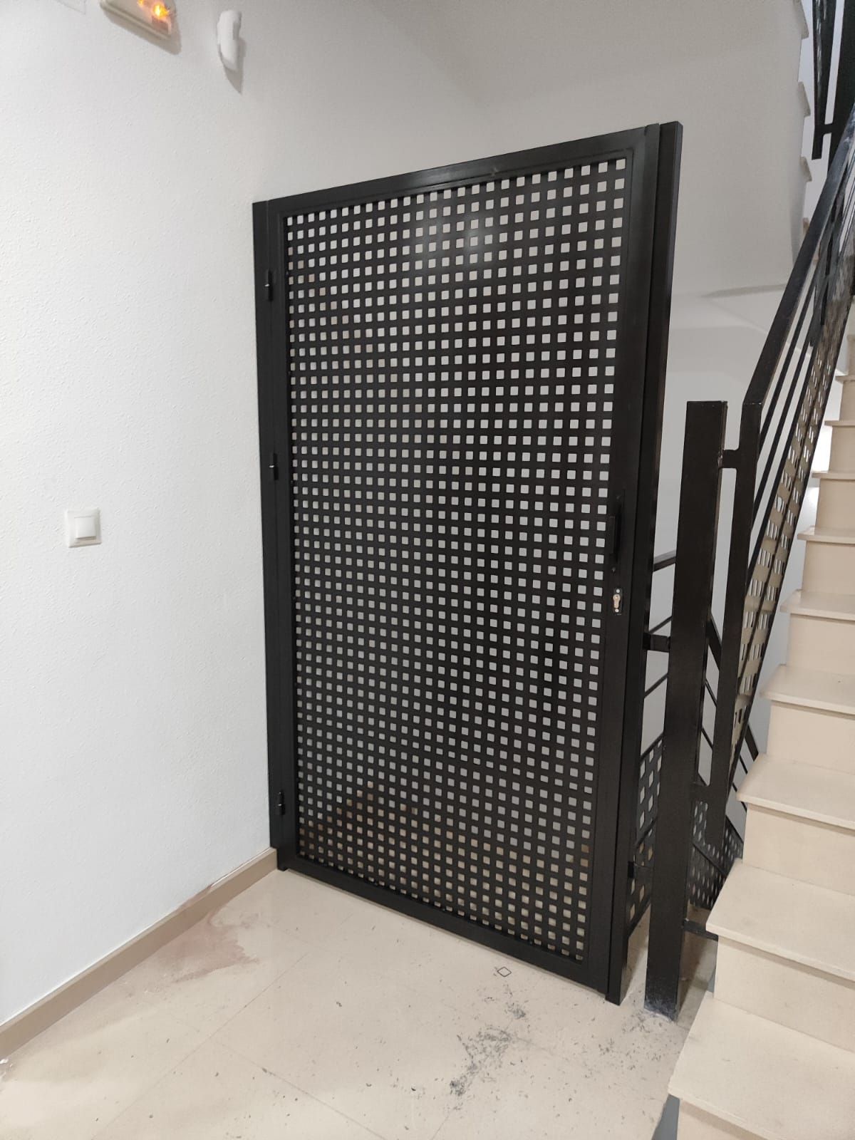 Una puerta negra está en un pasillo al lado de una escalera.