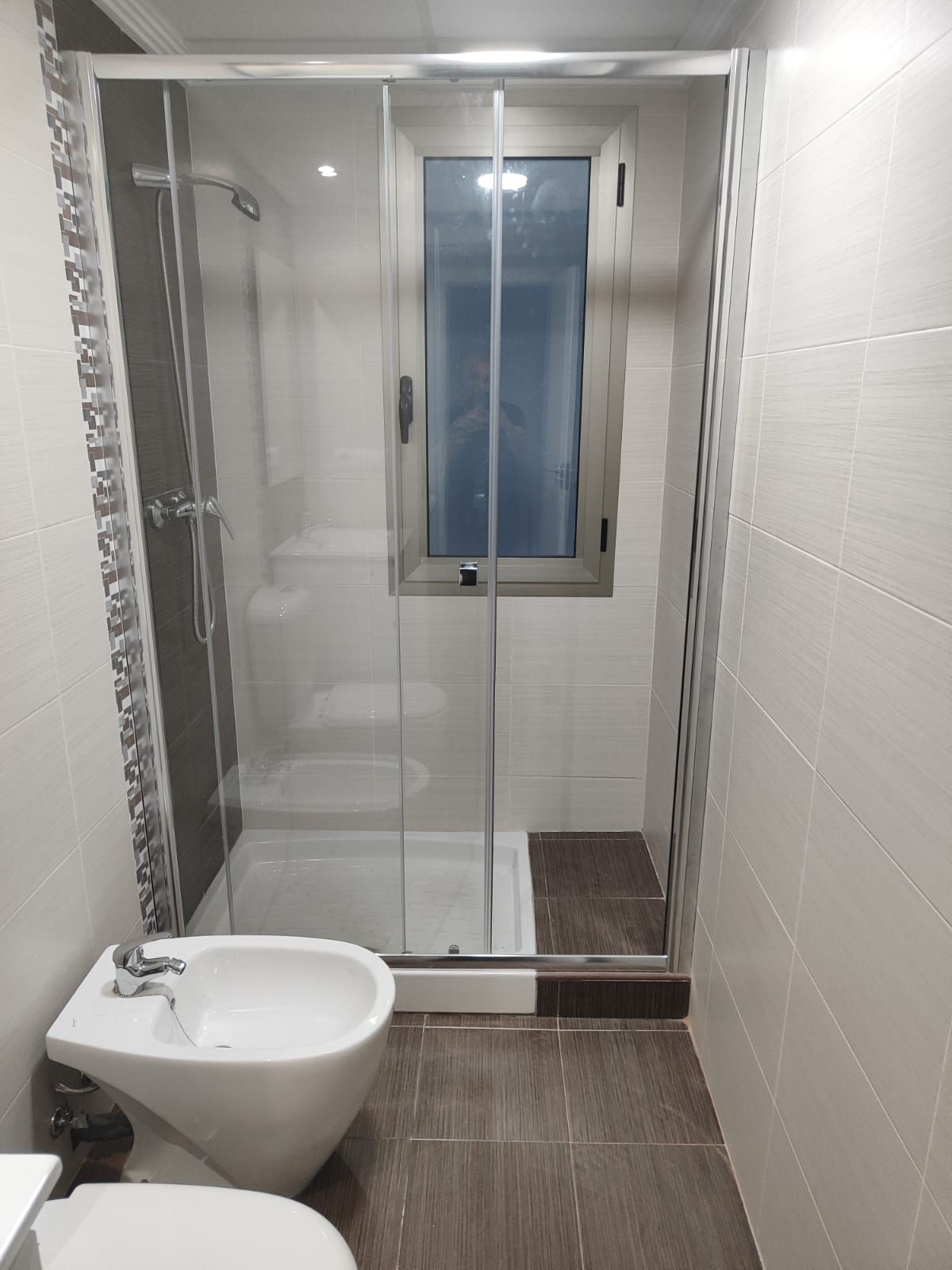 Un baño con inodoro, bidé y cabina de ducha.