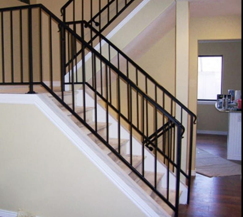 Una escalera con barandilla negra en una casa.