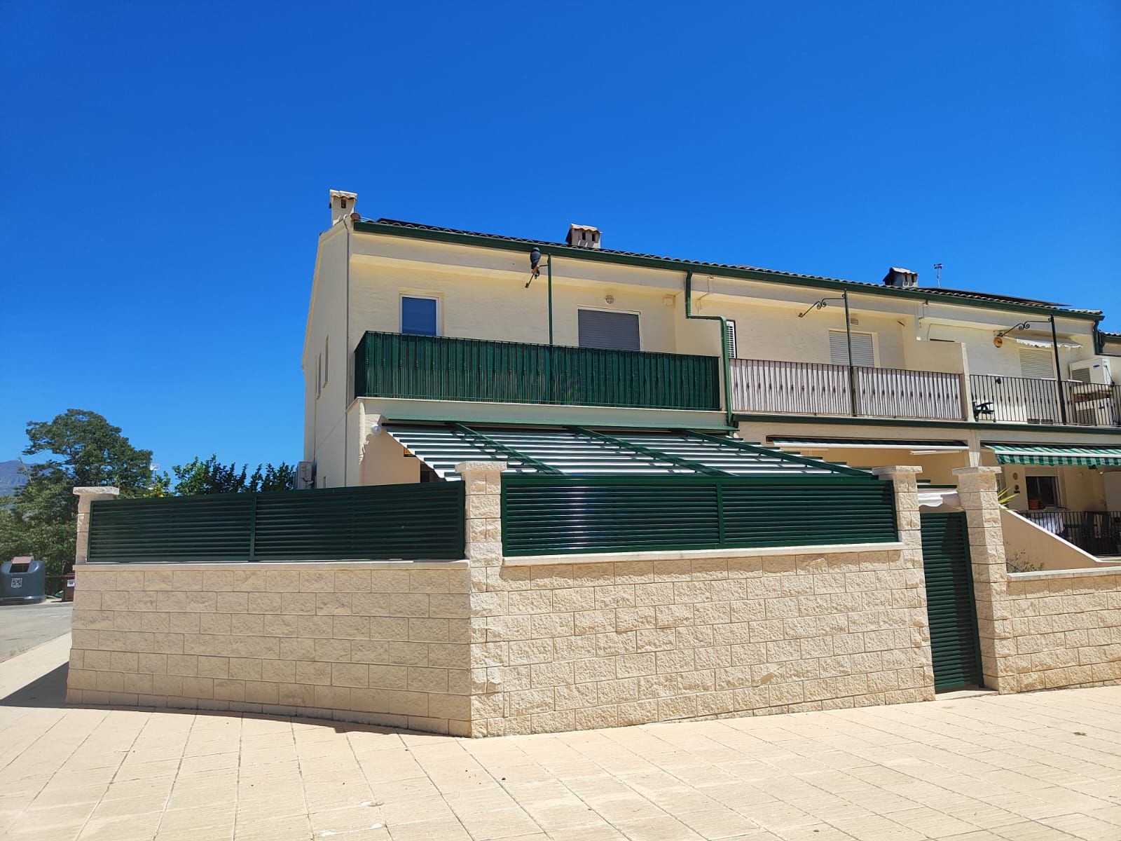 Una casa grande con una valla verde alrededor.