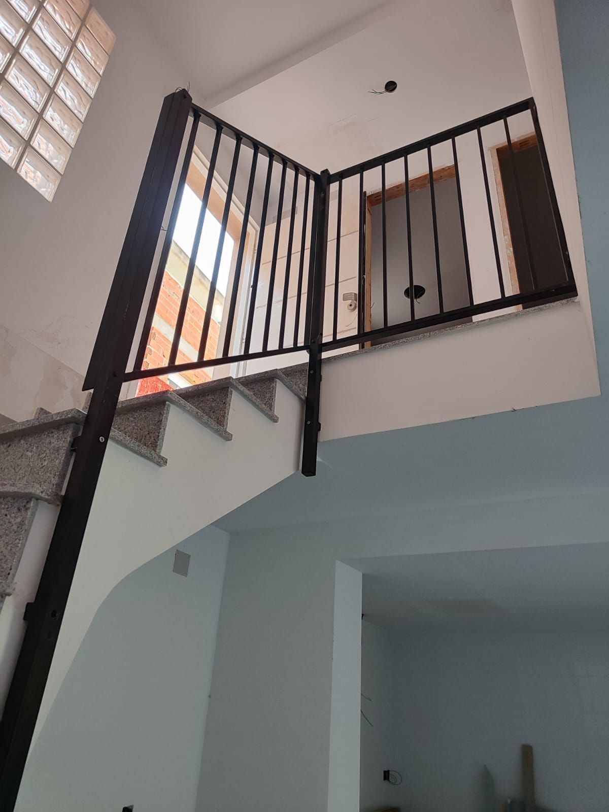 Una escalera con barandilla negra que conduce al segundo piso.