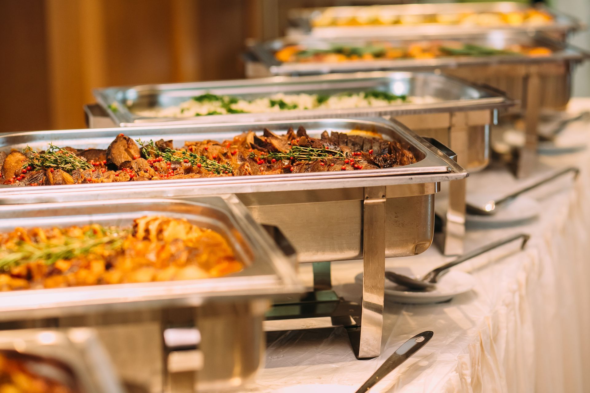 Buffet avec plateaux en acier inoxydable recouverts de plats chauds assortis lors d'un événement traiteur