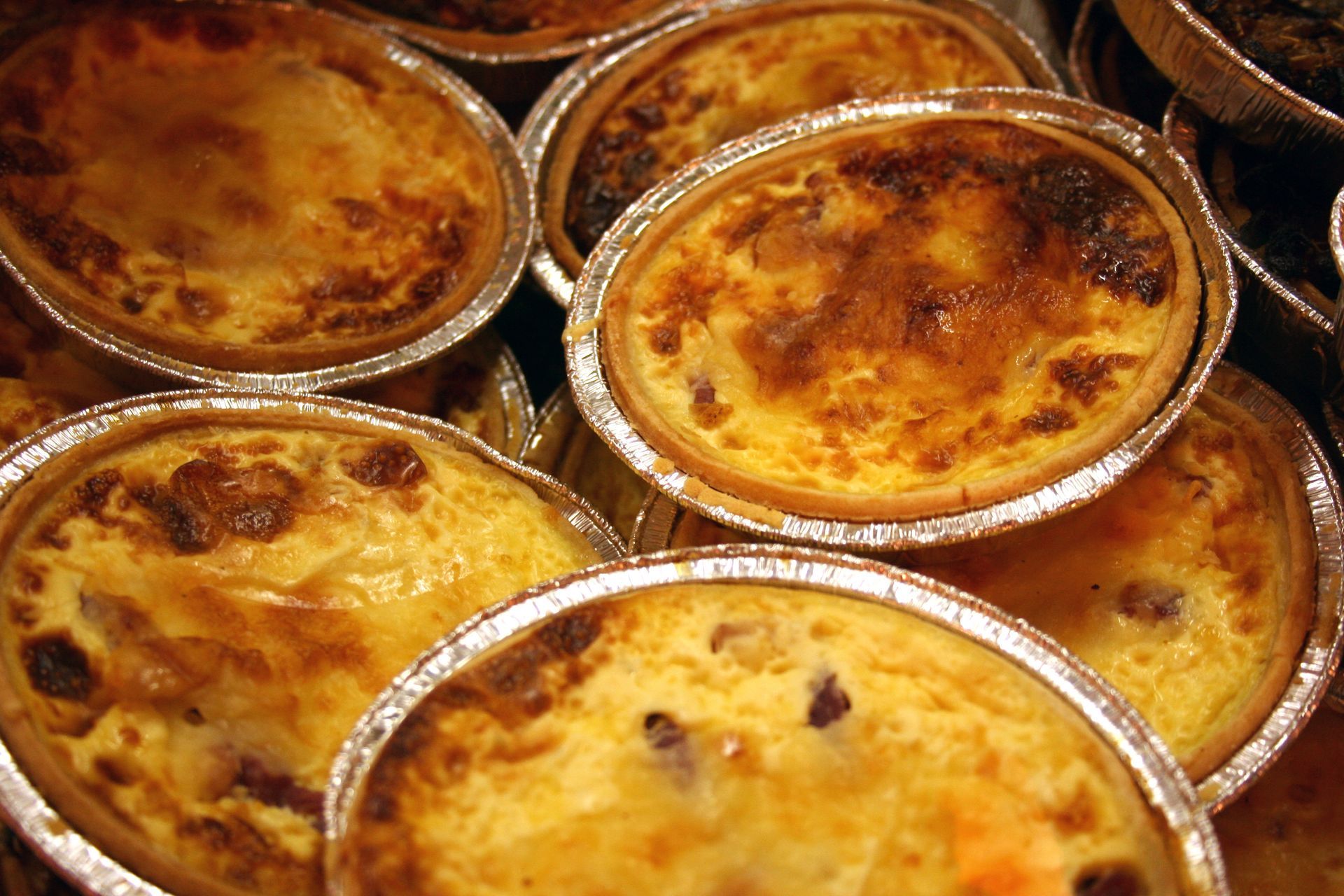 Petites tartes cuites au four dans des moules en aluminium, à la surface dorée, vues en gros plan