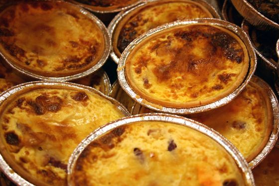 Petites tartes cuites au four dans des moules en aluminium, à la surface dorée, vues en gros plan