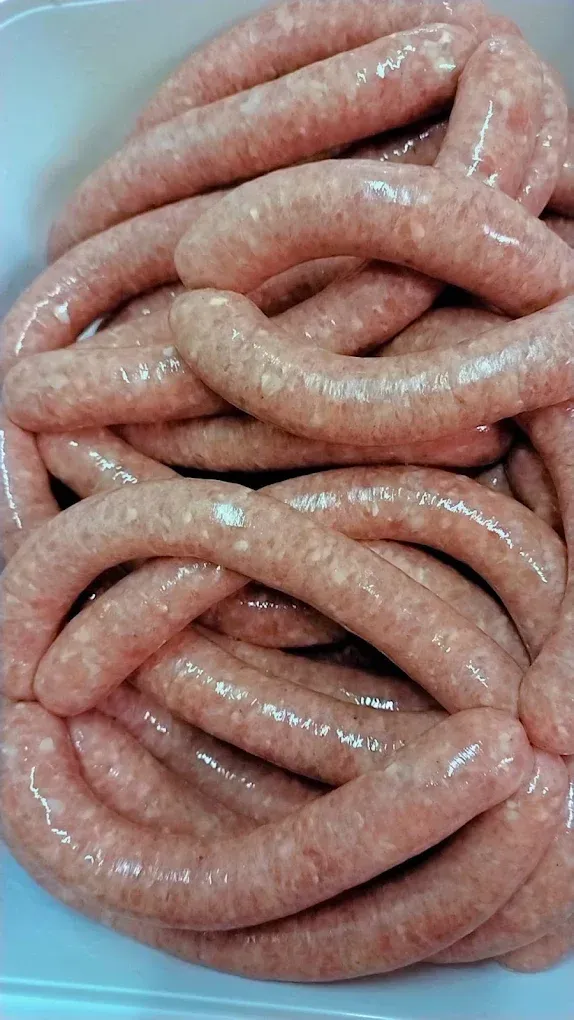 Saucisses crues enroulées, empilées en gros plan, rose pâle et brillantes.