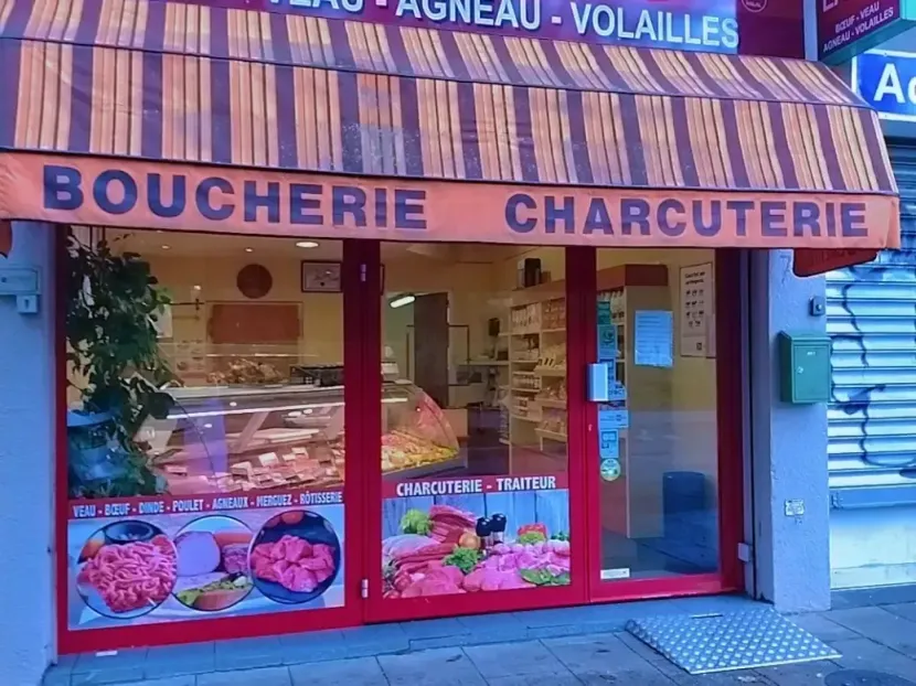 Façade de boucherie avec enseigne rouge et vitrines de viande.